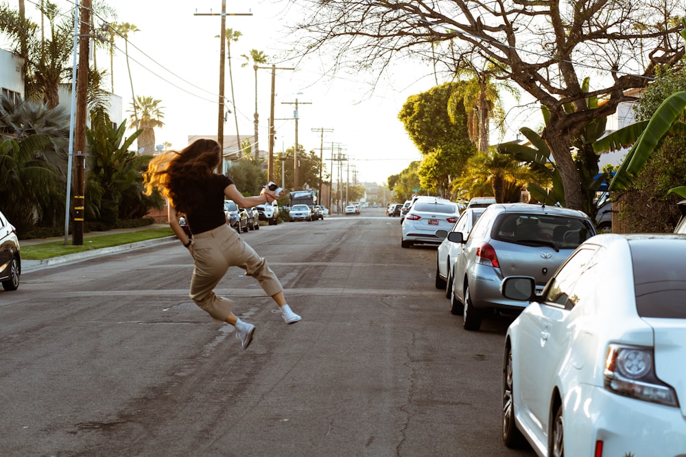 woman in black long sleeve shirt and white pants walking on street during daytime