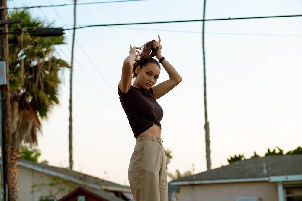 woman in black tank top and beige pants standing on electric wire during daytime