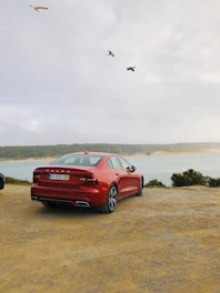 A spacious sedan with the ardi rental license plate cruising along a coastal road.