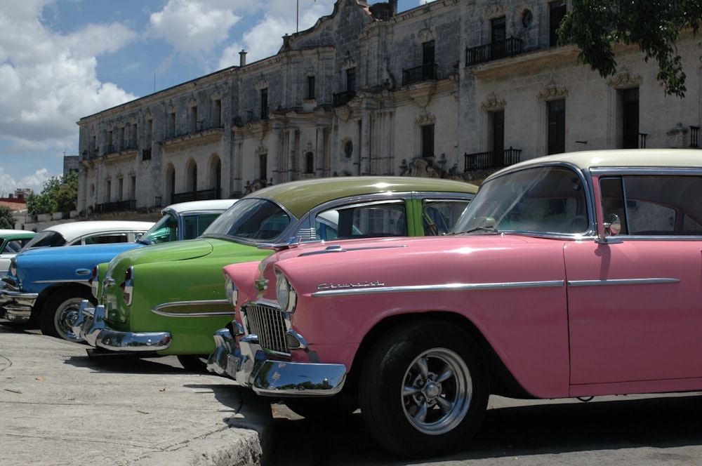 Rosa und grüner Oldtimer tagsüber neben braunem Betongebäude geparkt