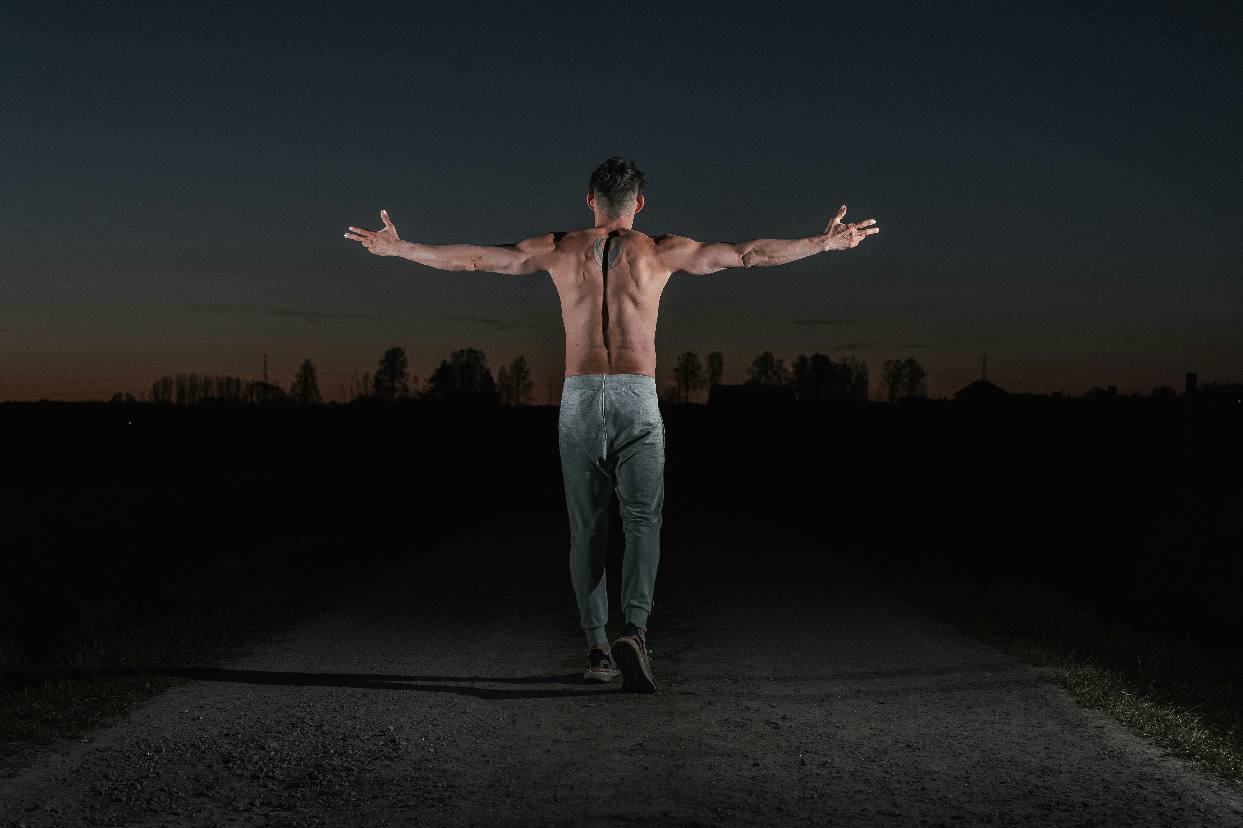 woman in white pants standing on black sand during night time