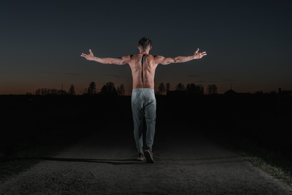 woman in white pants standing on black sand during night time