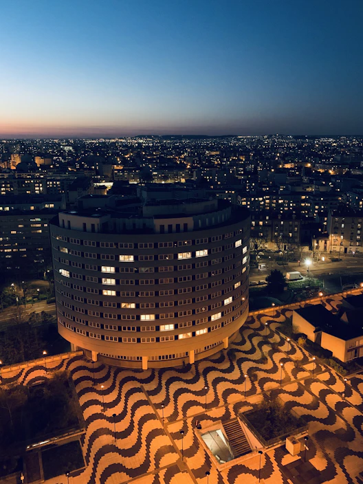 Close-up of hands assembling a detailed cityscape puzzle with bright lights at dusk.