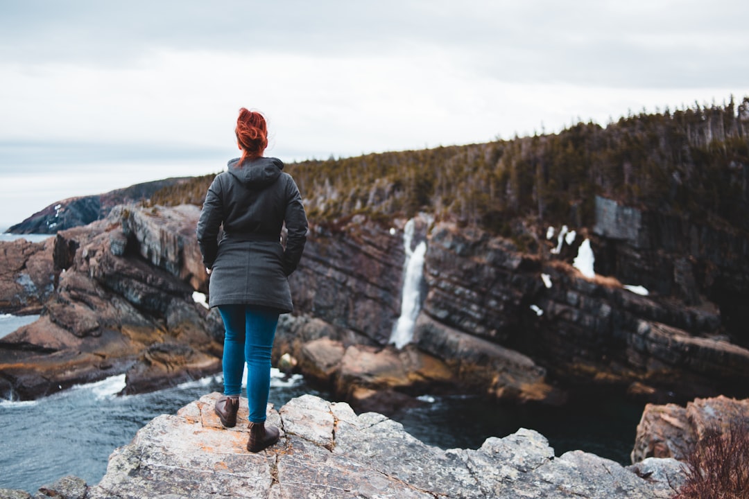 woman in black jacket standing on rocky mountain during daytime