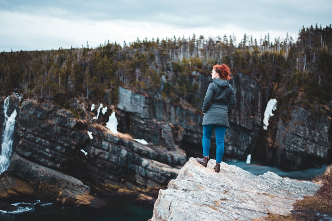 man and woman standing on rock formation near body of water during daytime