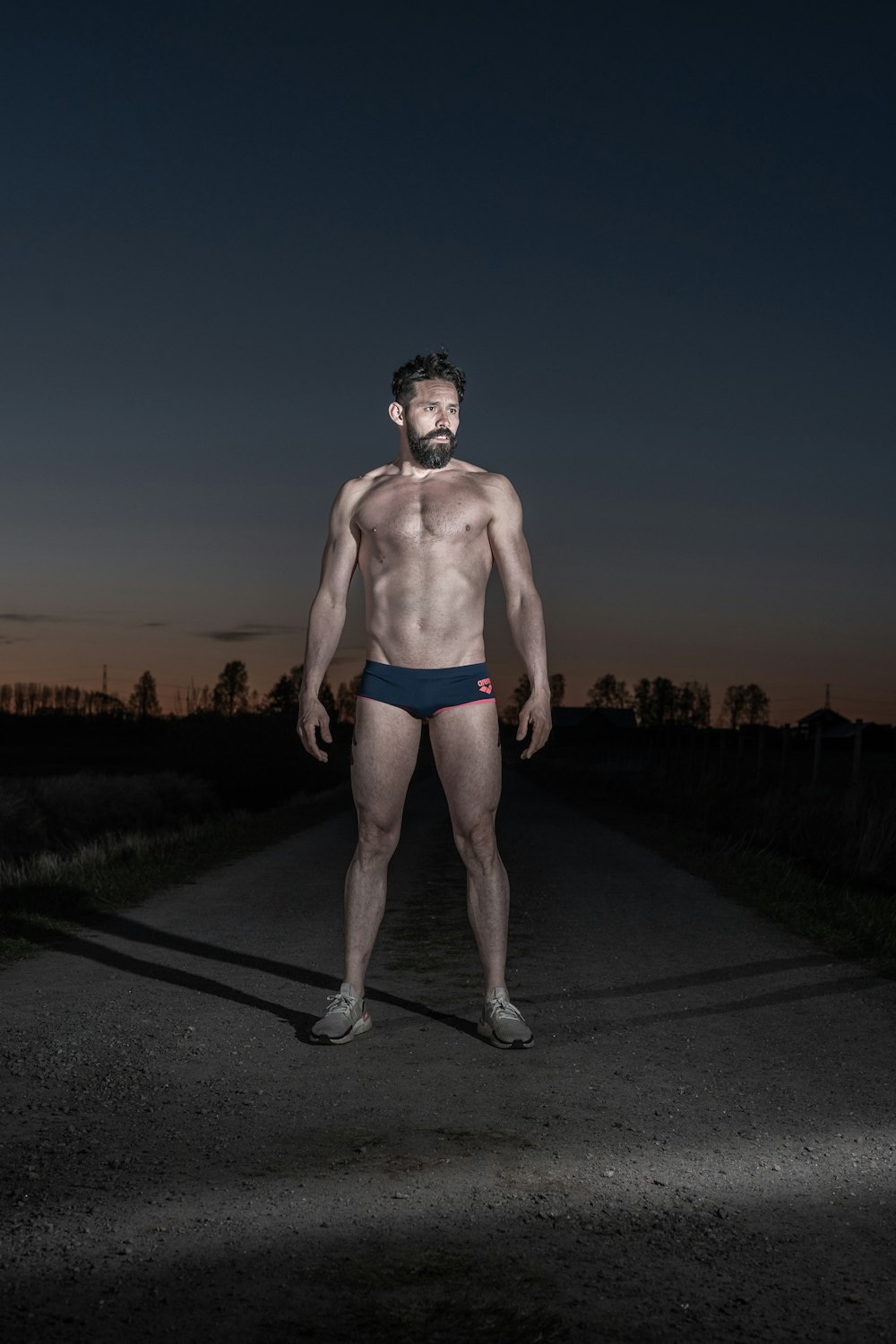 man in blue shorts standing on gray asphalt road during daytime