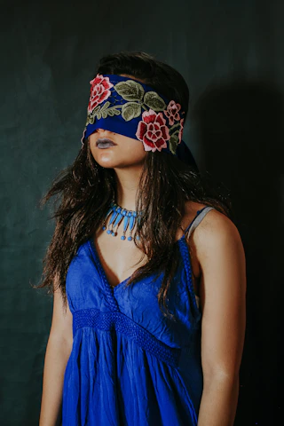 woman in blue sleeveless top wearing black and red floral headdress