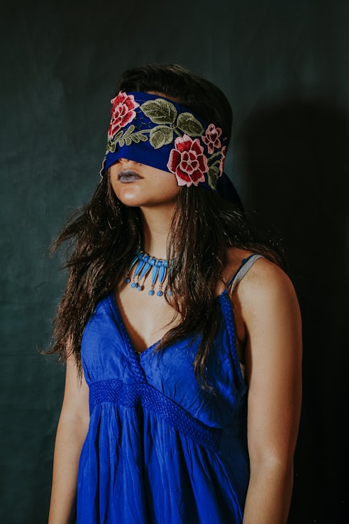 woman in blue sleeveless top wearing black and red floral headdress