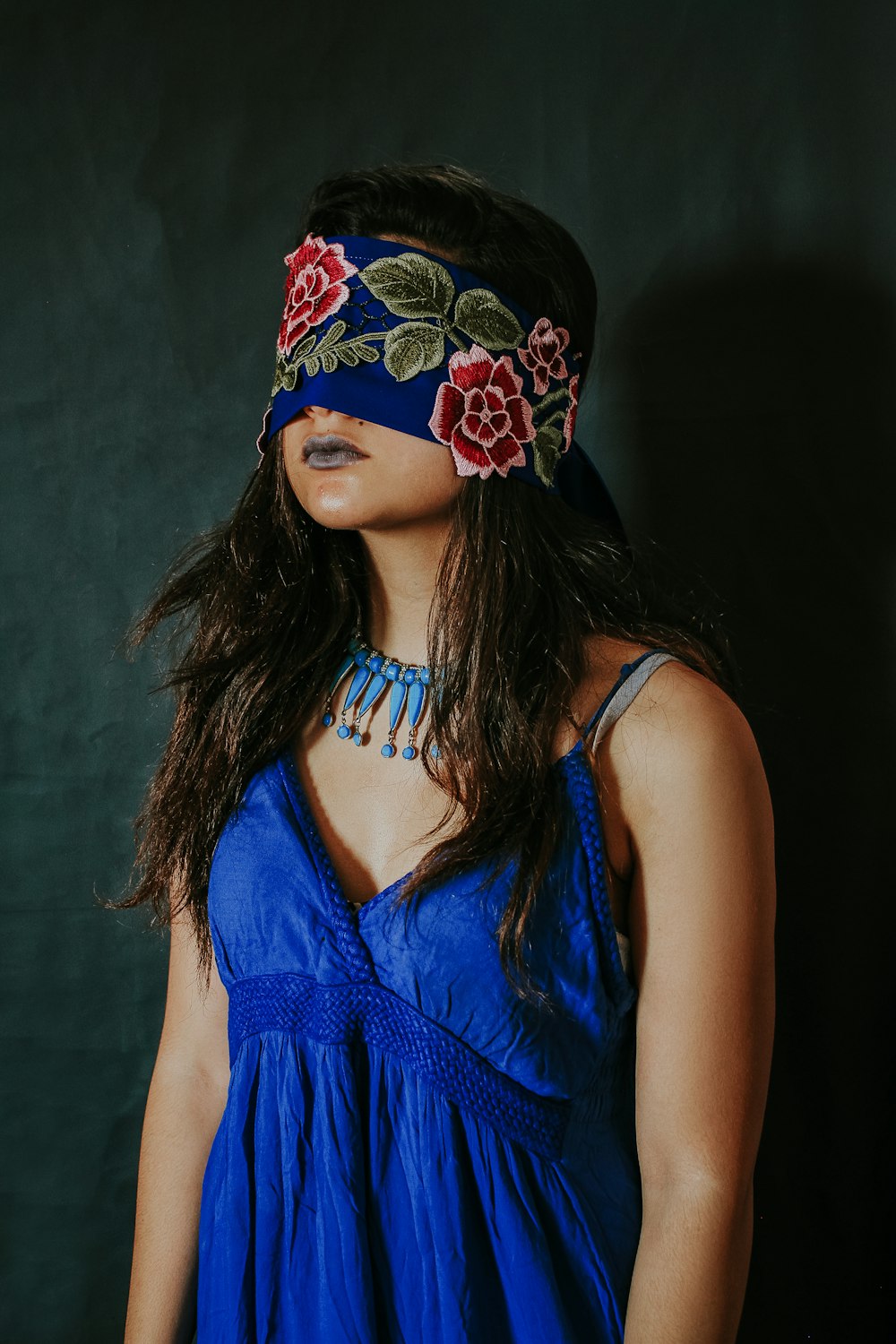 woman in blue sleeveless top wearing black and red floral headdress