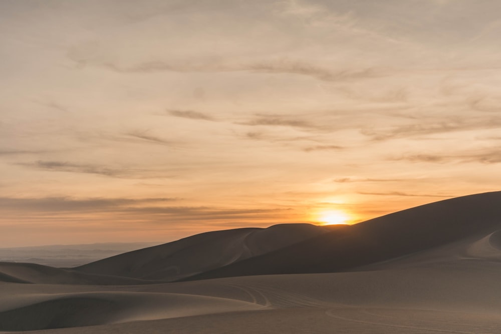 areia branca sob o céu nublado durante o pôr do sol