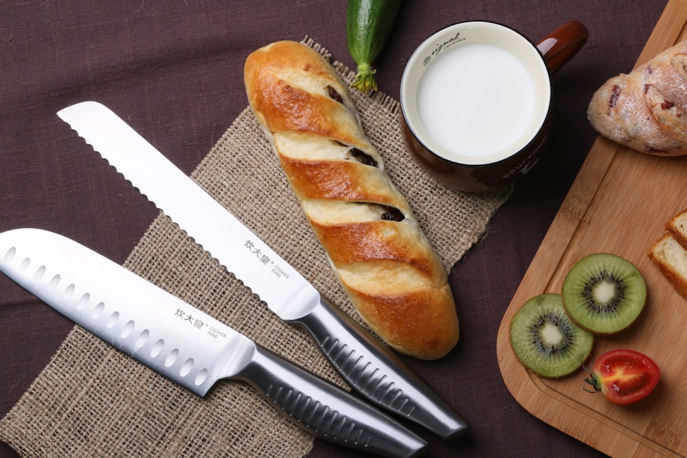 bread on brown wooden chopping board beside stainless steel bread knife and white ceramic plate