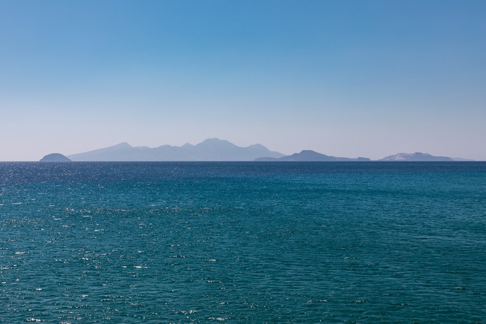 body of water near mountain during daytime