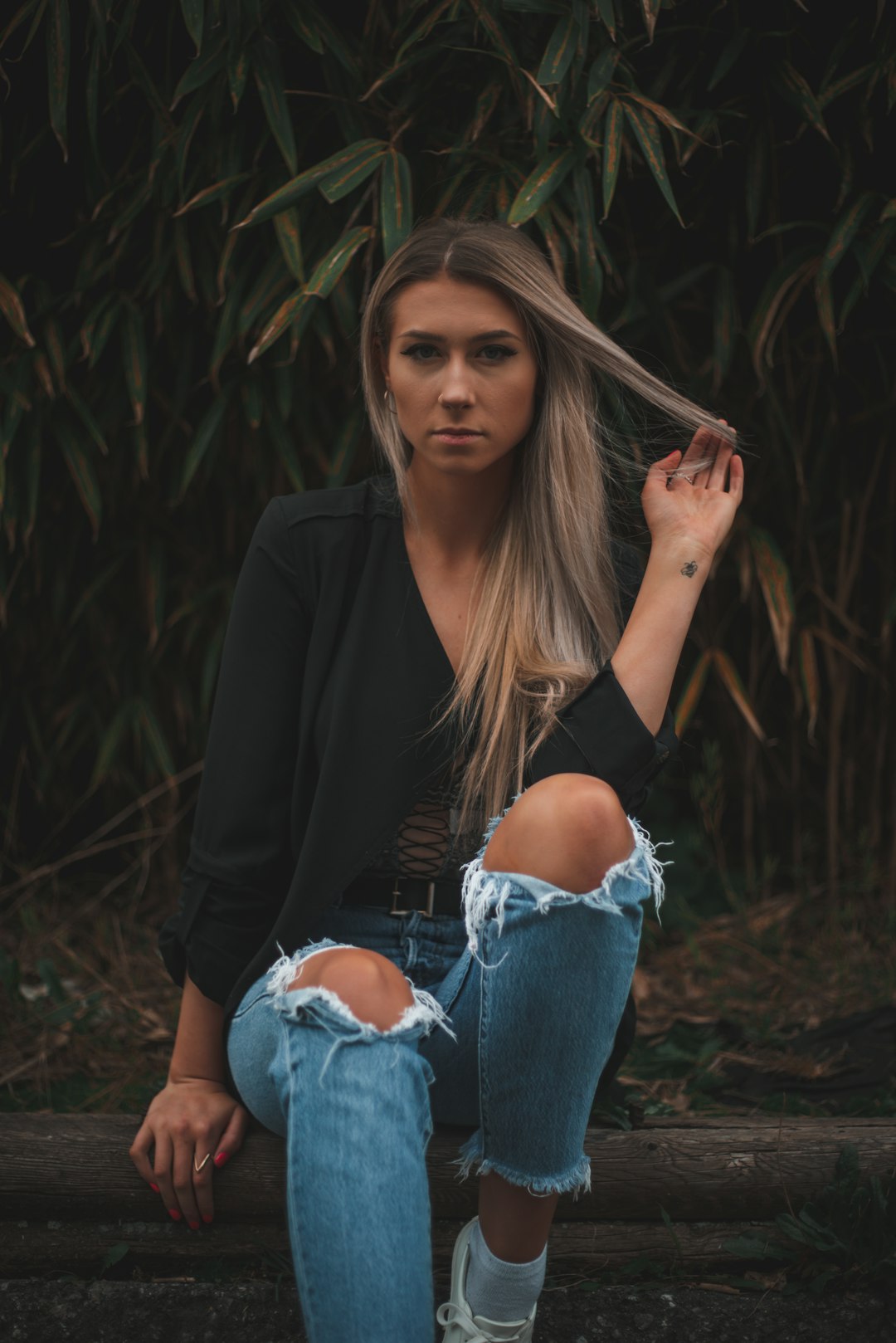 woman in black long sleeve shirt and blue denim jeans sitting on ground