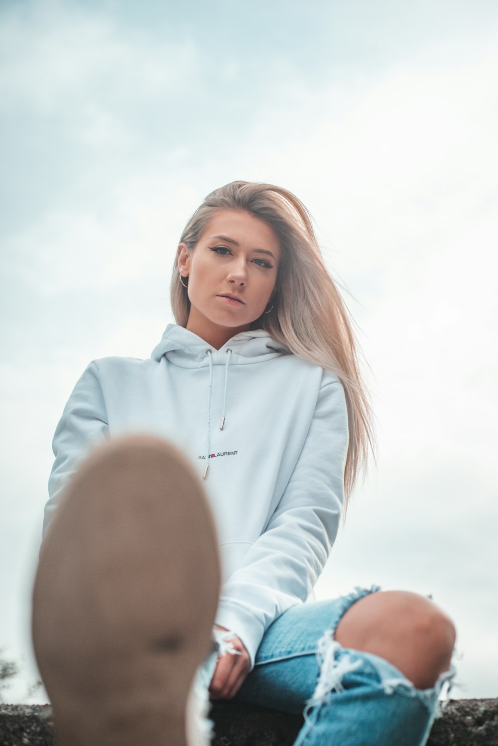 woman in white hoodie standing under white clouds during daytime