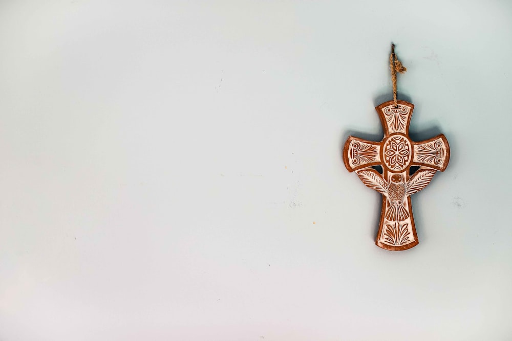 gold cross pendant on white surface