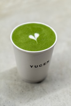 A minimalist matcha tea set with a smiling cup and delicate doodle leaves on a soft pastel background.