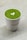 A cup filled with vibrant green matcha tea featuring a heart-shaped latte art on the surface, set against a light, neutral background. The cup has the word 'YUGEN' printed on it.