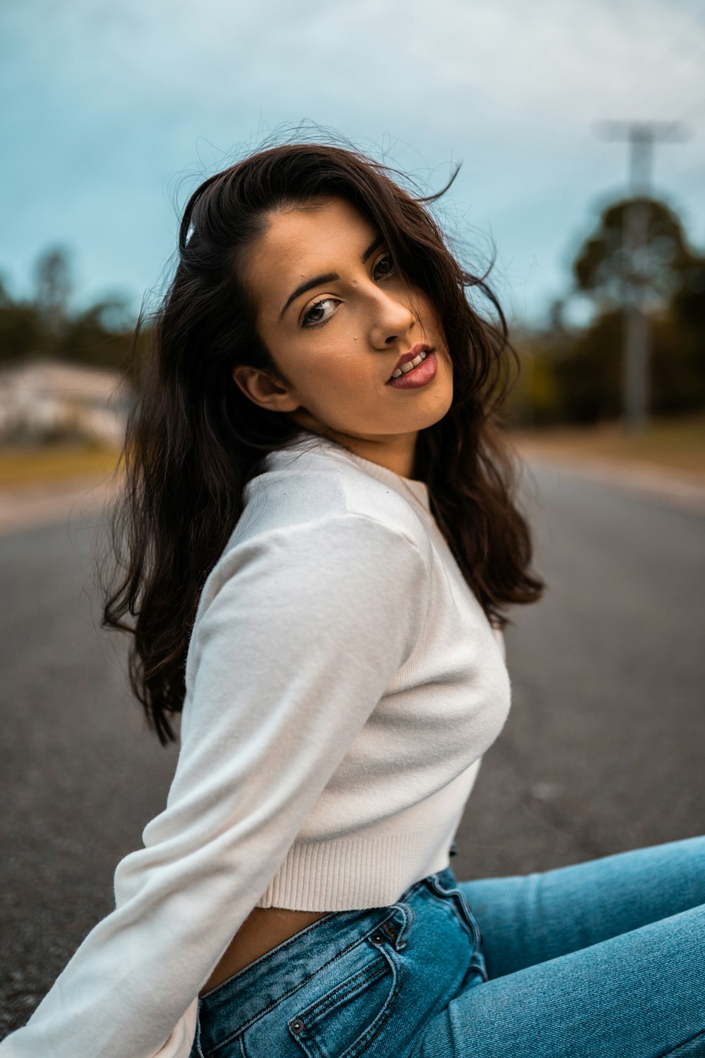 mulher na camisa branca da manga comprida que está na estrada durante o dia