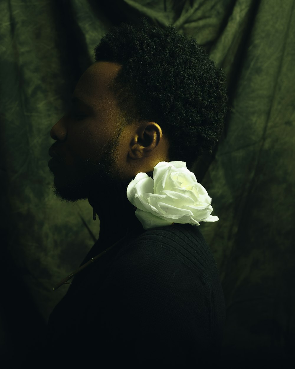 man in black shirt holding white rose