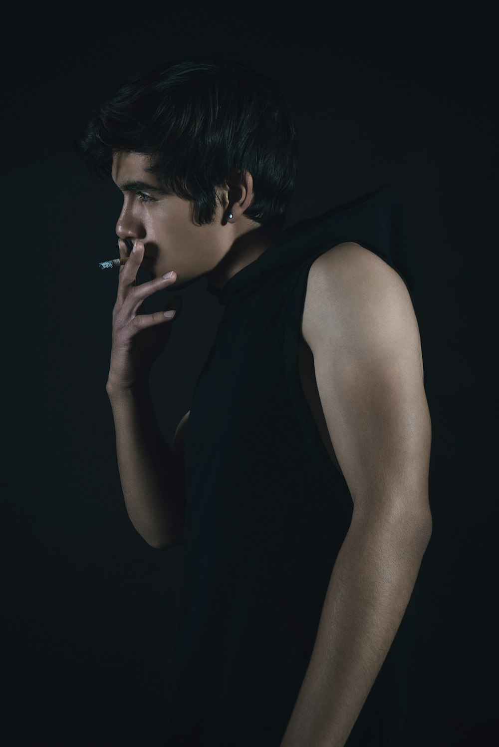 man in black tank top smoking cigarette