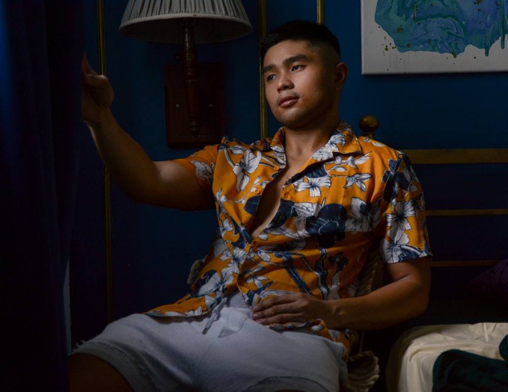 man in yellow and white floral button up shirt sitting on chair