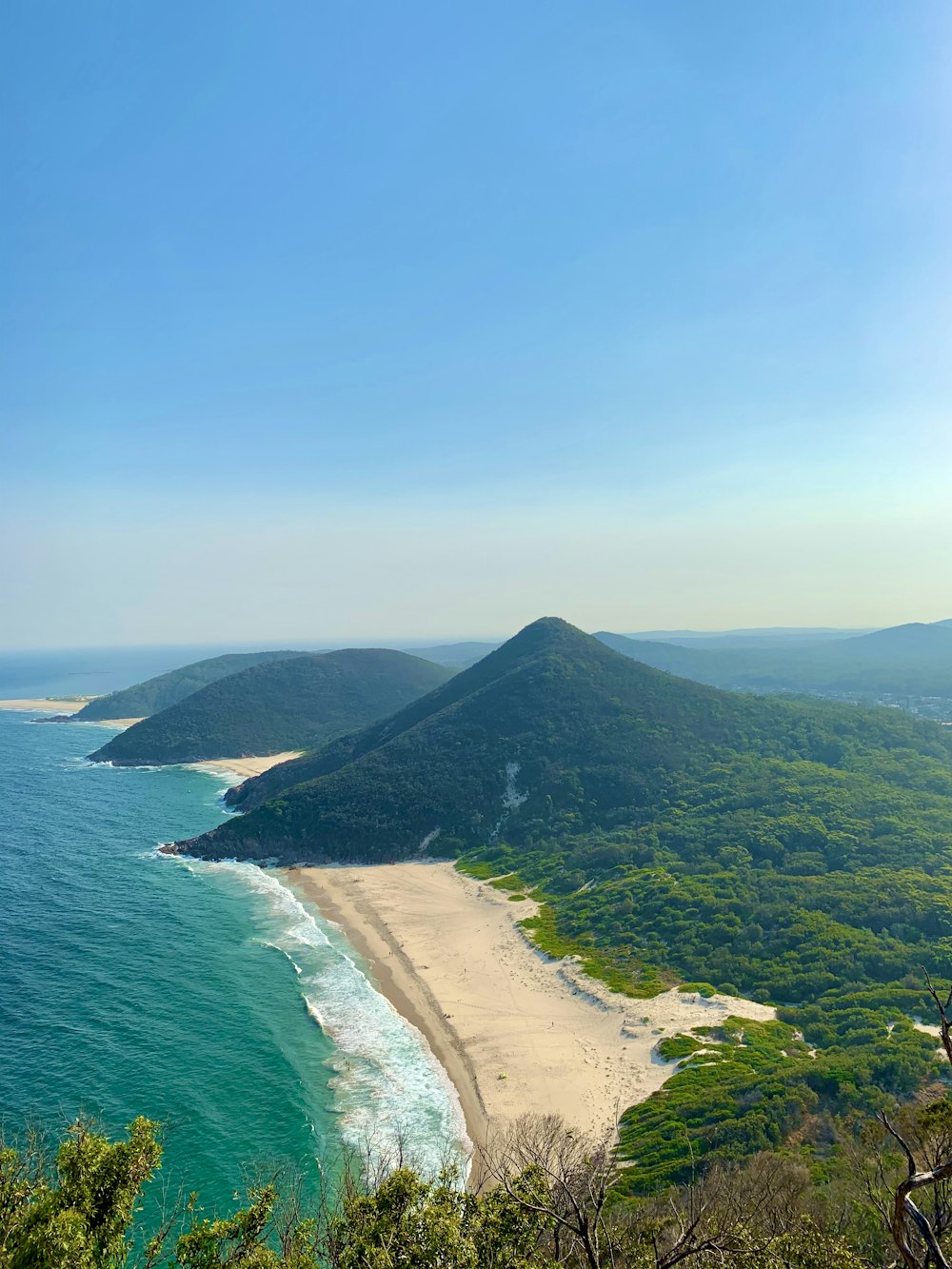 green mountain beside body of water during daytime