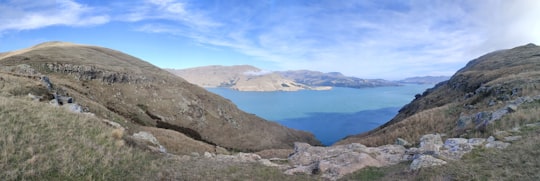 blue lake in the middle of mountains during daytime in Godley Head Road New Zealand