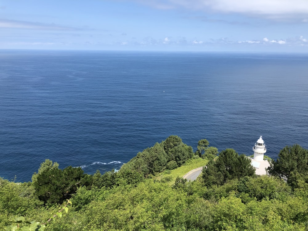 edificio in cemento bianco in cima alla collina vicino allo specchio d'acqua durante il giorno