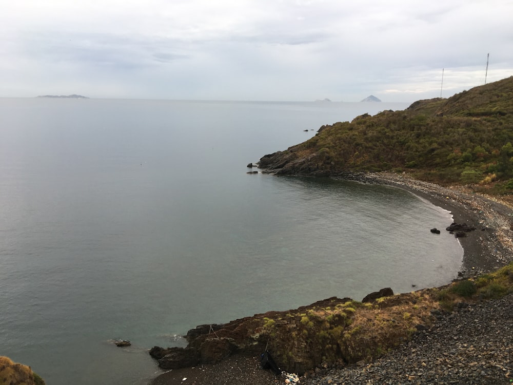 green and brown mountain beside body of water during daytime