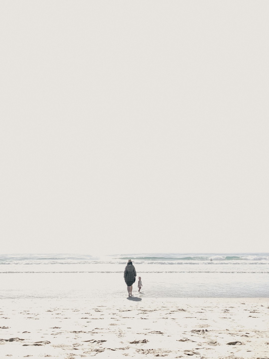 man in black shirt and blue denim jeans walking on beach during daytime