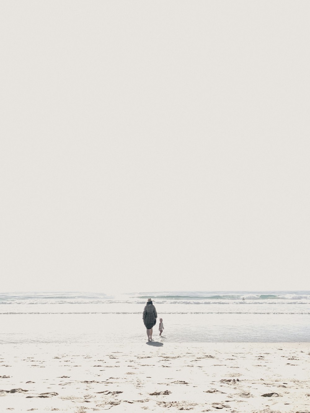 man in black shirt and blue denim jeans walking on beach during daytime