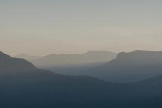A serene mountain range at dawn with soft light casting long shadows over the peaks.