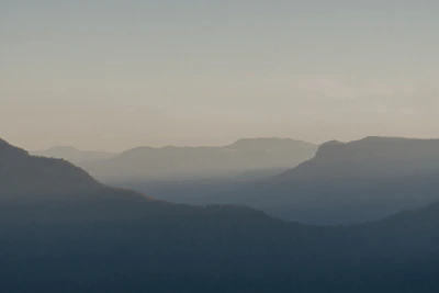 Golden hour light casting long shadows over a misty mountain range.