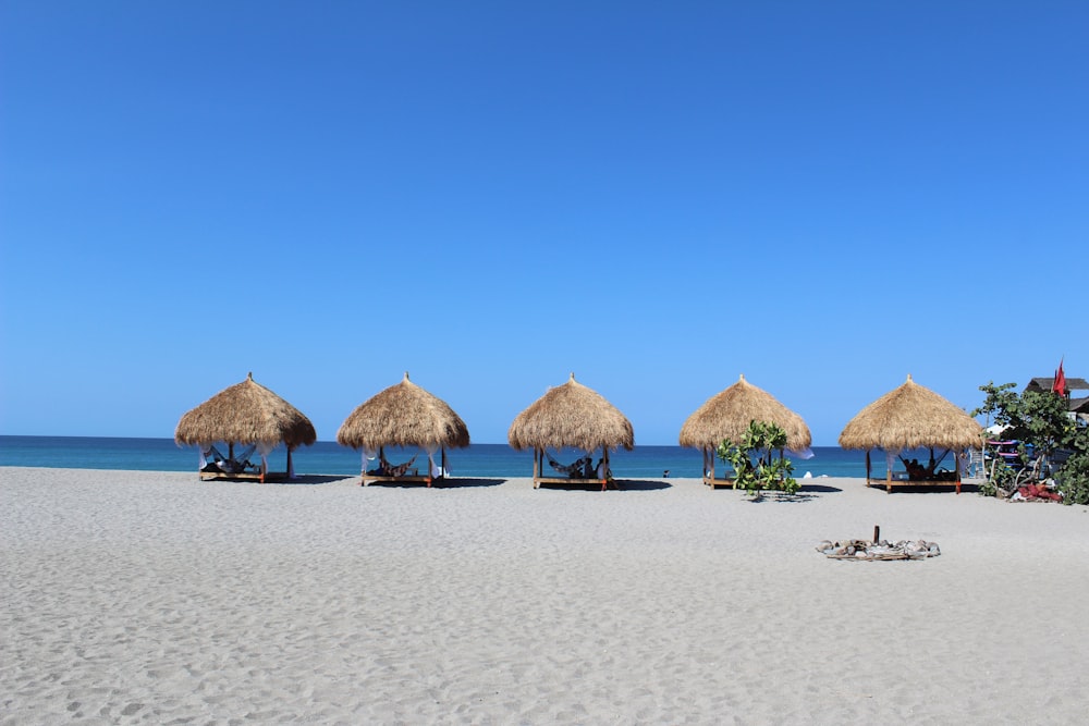 brown wooden beach umbrellas on beach during daytime