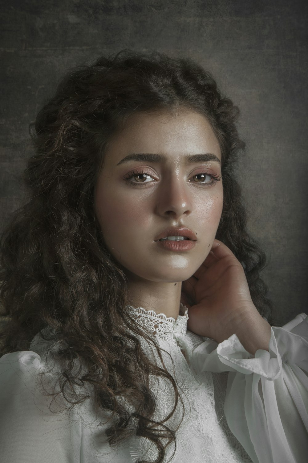 woman in white dress leaning on gray wall