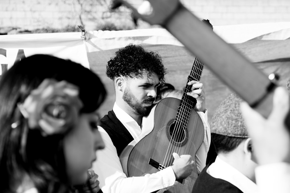 hombre con camisa de vestir blanca tocando la guitarra acústica