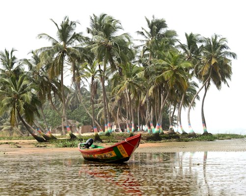 Red boat on body of water near green palm trees during daytime — Accra, Ghana