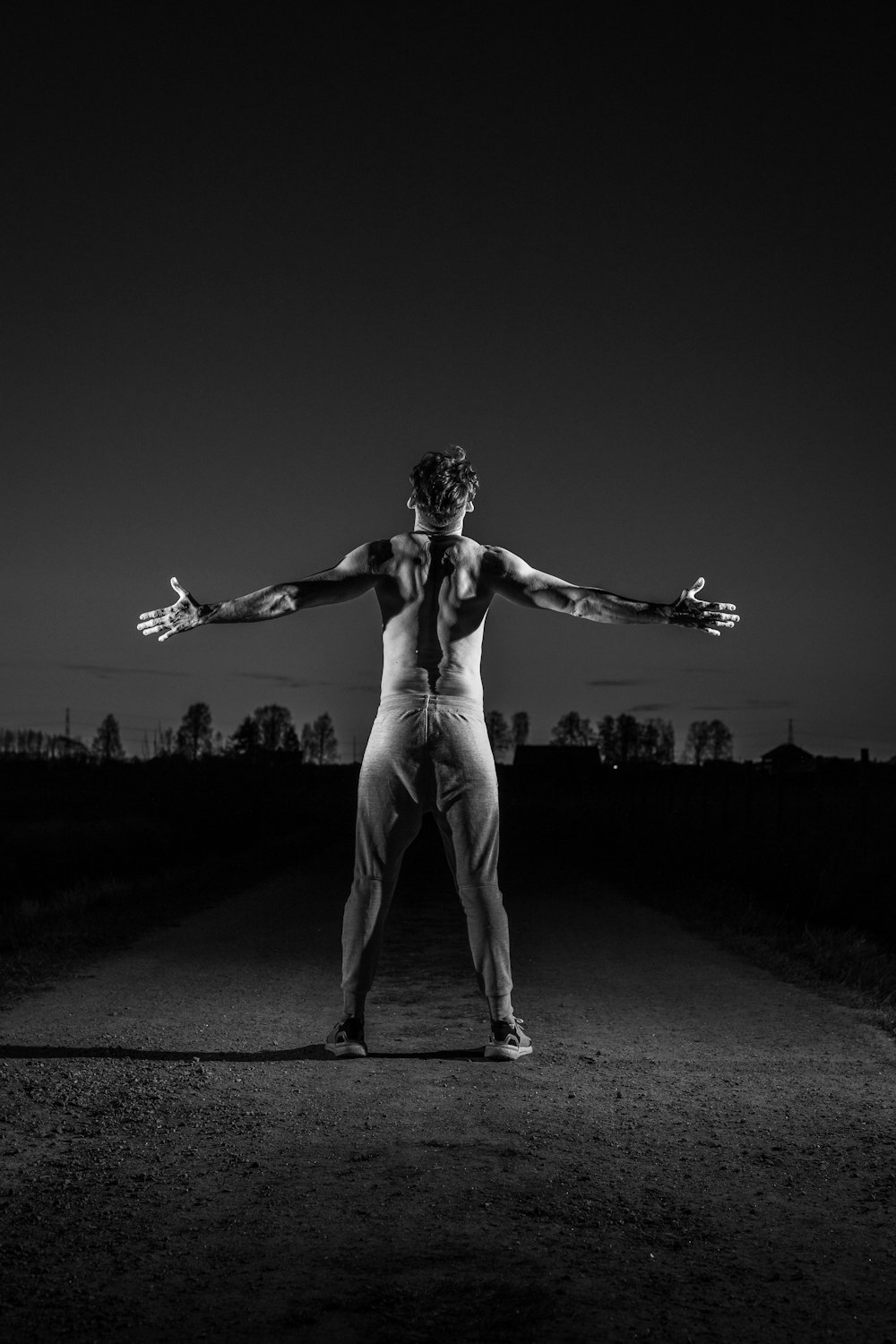grayscale photo of woman in white pants standing on road