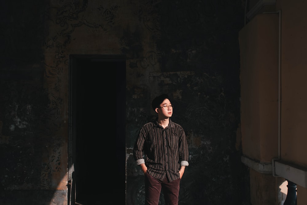 man in black and white checkered button up shirt standing in front of brown wooden door