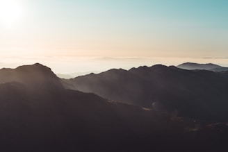 A serene mountain landscape at sunrise with soft clouds.