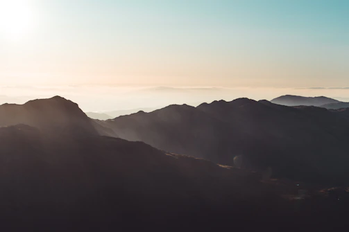 A serene mountain landscape with soft morning light casting gentle shadows.