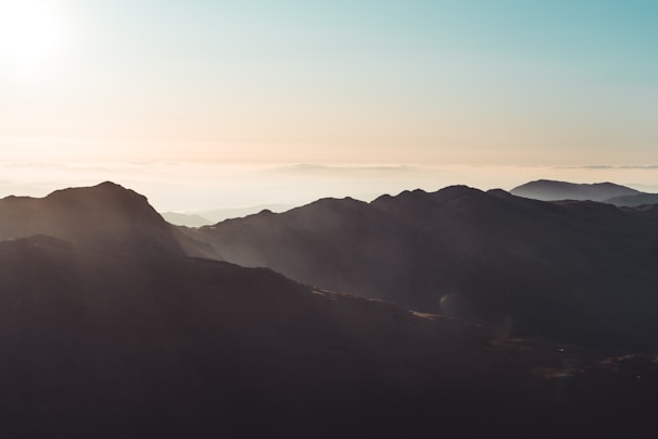 A serene mountain landscape at sunrise with soft clouds.