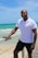 man in white polo shirt and black pants standing on beach during daytime