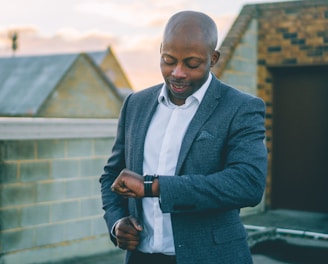 man in gray suit jacket holding black smartphone