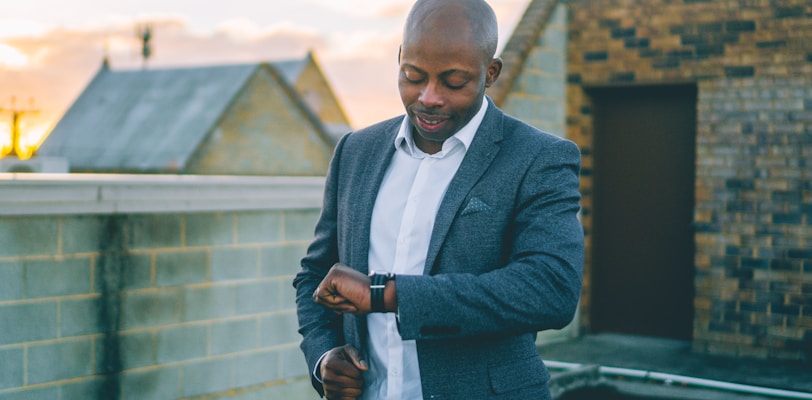 man in gray suit jacket holding black smartphone