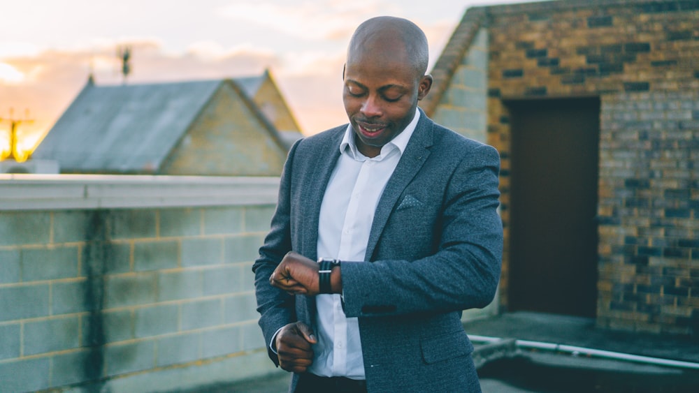 man in gray suit jacket holding black smartphone