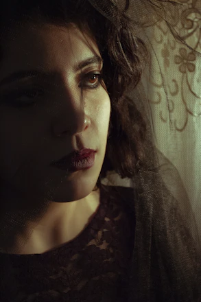 A sensual and elegant woman in soft lighting, embodying mystery and allure.