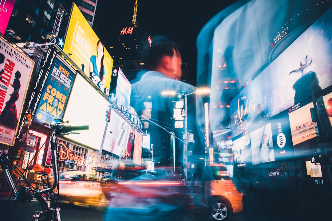 man in blue shirt standing near cars during night time