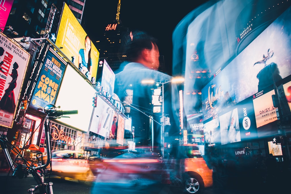 man in blue shirt standing near cars during night time