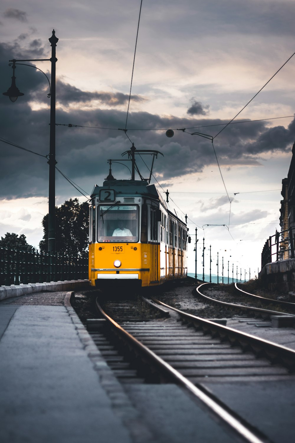 a yellow train traveling down train tracks under a cloudy sky
